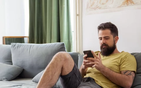 Homem a usar o telemóvel no sofá
