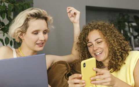 Mulheres a olhar o telemóvel e sorrir