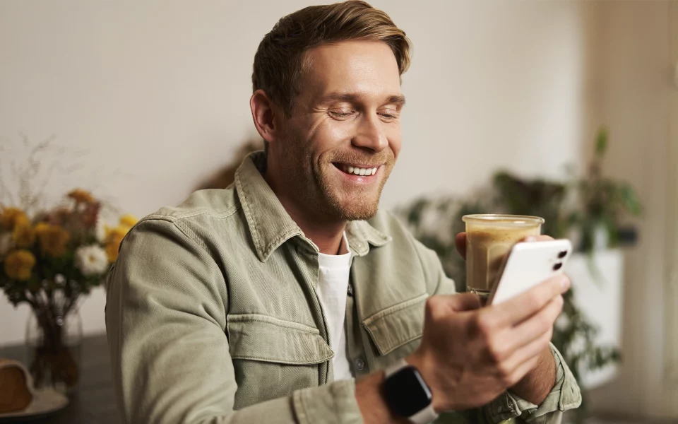 Homem a segurar o telemóvel a sorrir