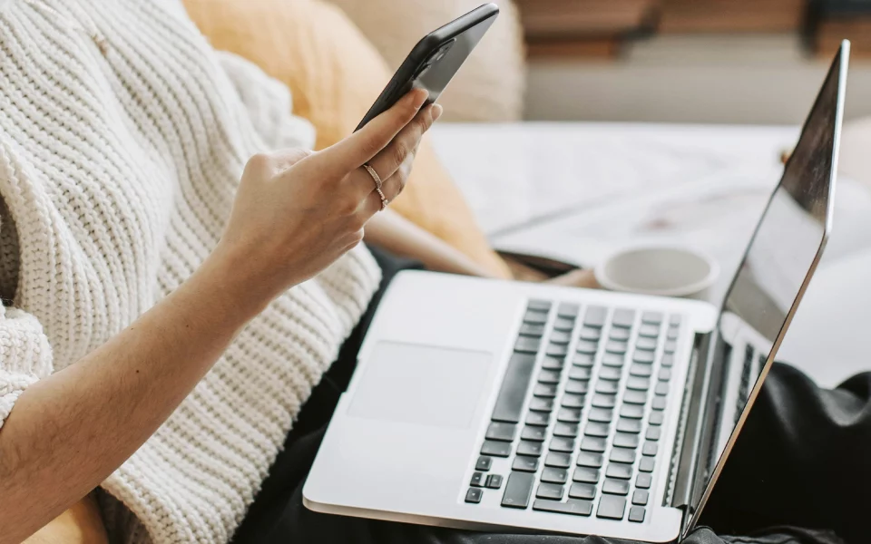 Mulher jovem a usar o telemóvel e computador portátil