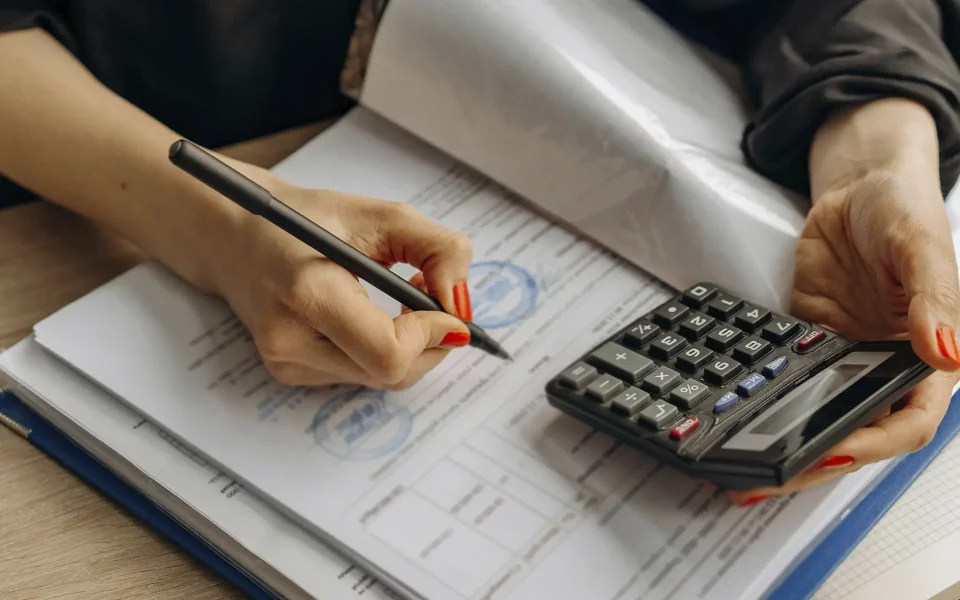 Mulher a fazer calculos na calculadora e a preencher documentação