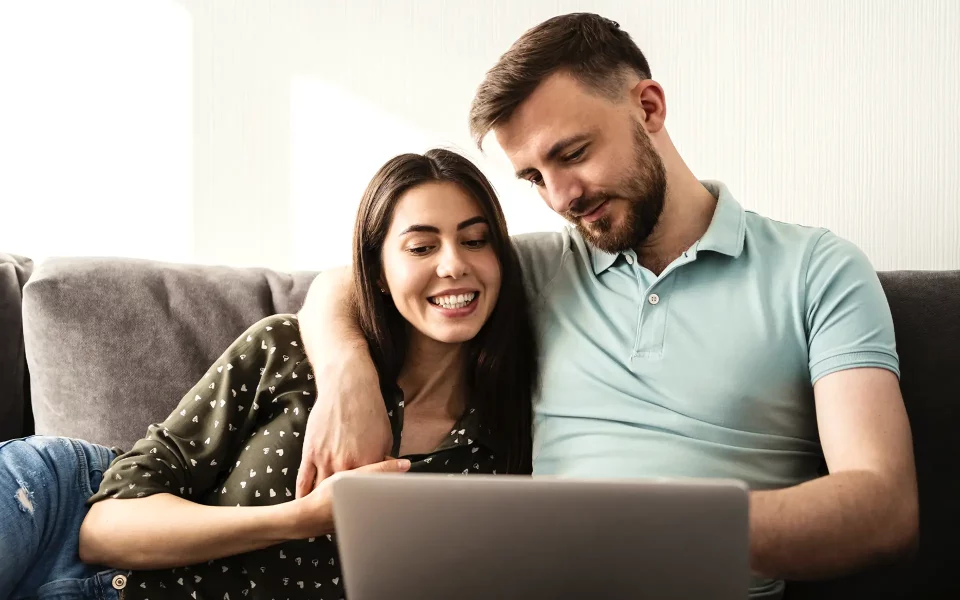 Casal no sofá a usar o computador portátil