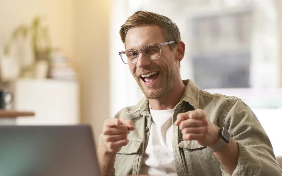 homem a sorrir e piscar para o computador portátil