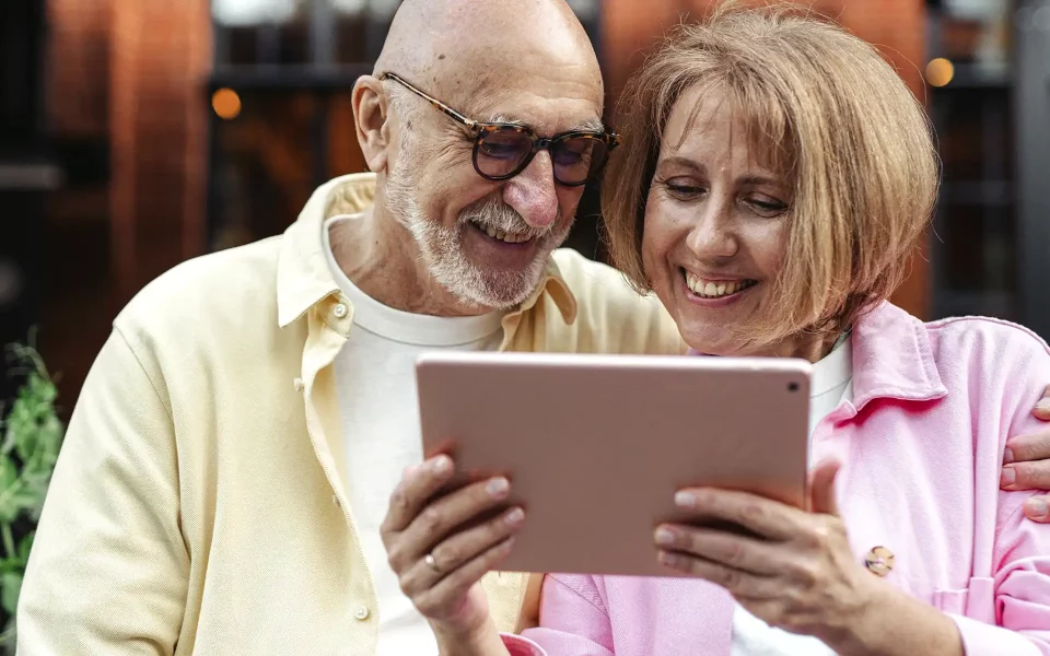 Casal senior a sorrir com o tablet na mao