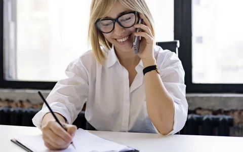 Mulher a segurar o telemóvel a sorrir