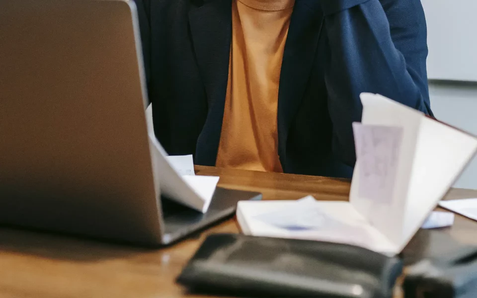 Homem a usar o computador portátil na secretaria com documentos