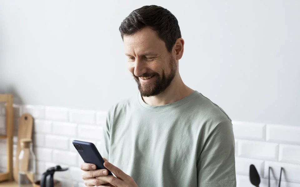 Homem a usar o telemóvel a sorrir