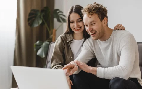 Vista frontal de um casal sorridente fazendo planos para reformar a casa juntos