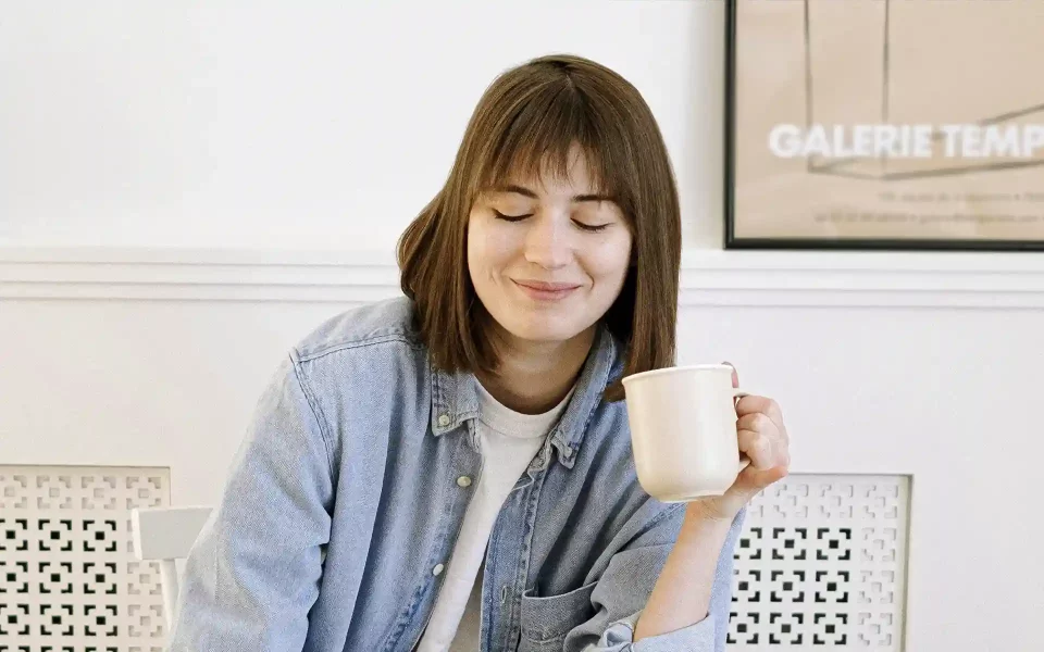 Mulher a sorrir com a chavena de café na mão