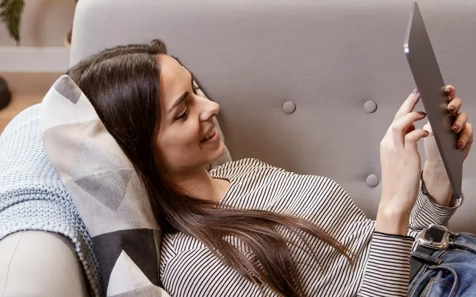 Mulher a usar o tablet no sofá