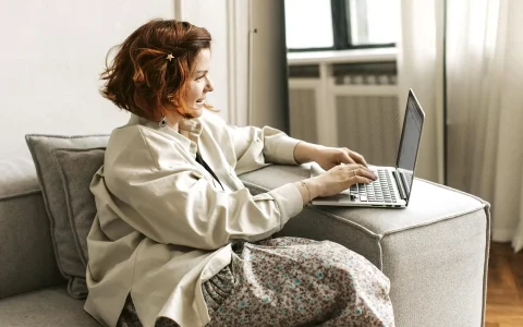 Mulher a usar o computador porátil no sofá da sala de estar